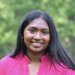 Krithika Santhanam Young woman wearing a vibrant magenta top, against a tree lined background