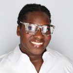 African American young woman with glasses with short hair and glasses and wide simile. She is wearing a white shirt